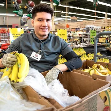 A Bridges participant stocking produce at a grocery store