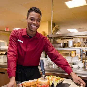 A Bridges participant serving food at a restaurant
